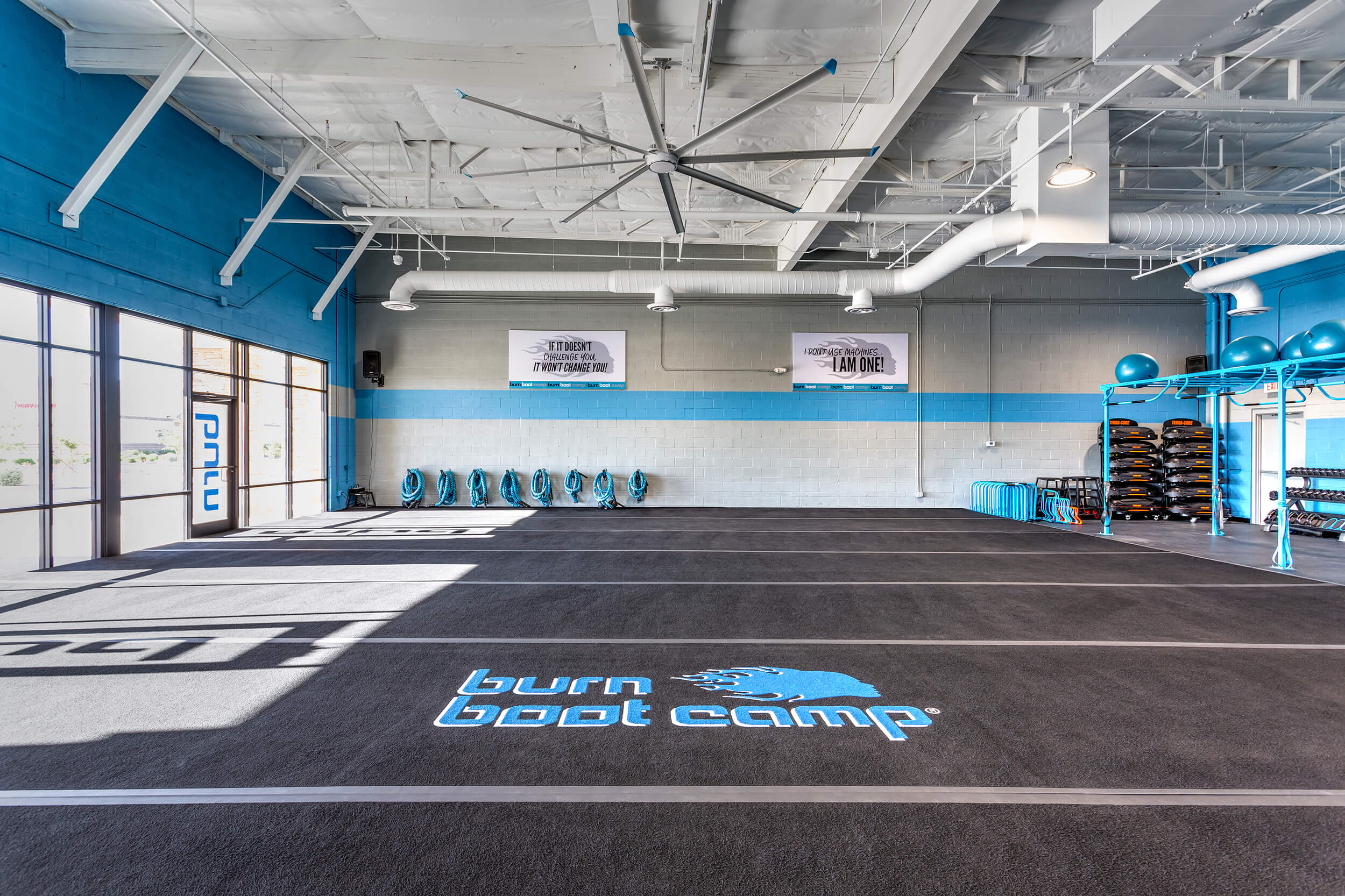 großer-decken-luefter-sporthalle-wingstec-deutschland Fitnesscenter mit großem Deckenventilator von Bigassfans mit blauen akzenten