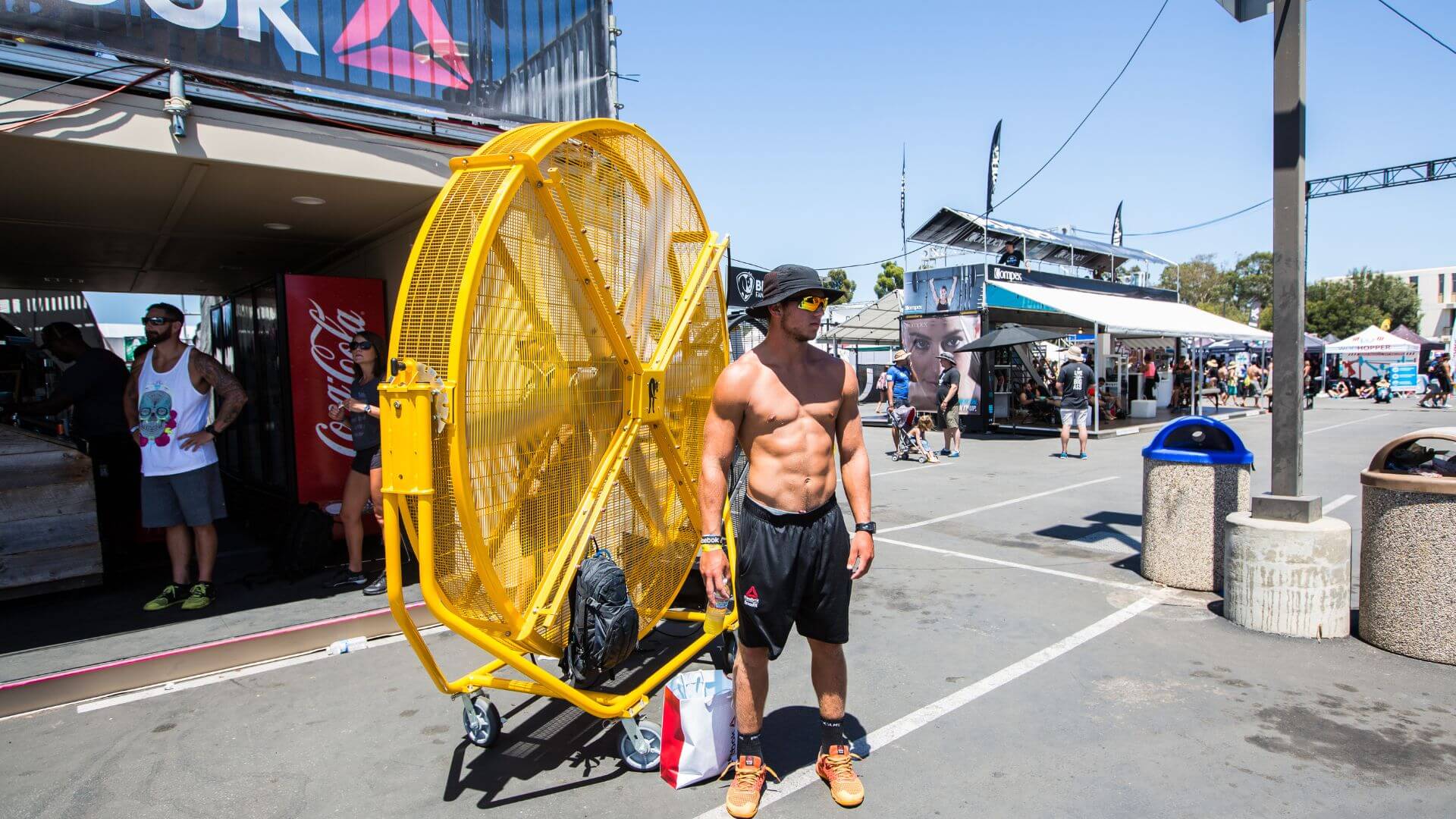 Effektive Kühlung von Sportlern mit dem leistungsstarken Big Ass Fans Ventilator Ein junger CrossFiter steht vor einem großen Ventilator von BigAssFans in Gelb und sorgt für eine kühle Brise und eine angenehme Abkühlung.